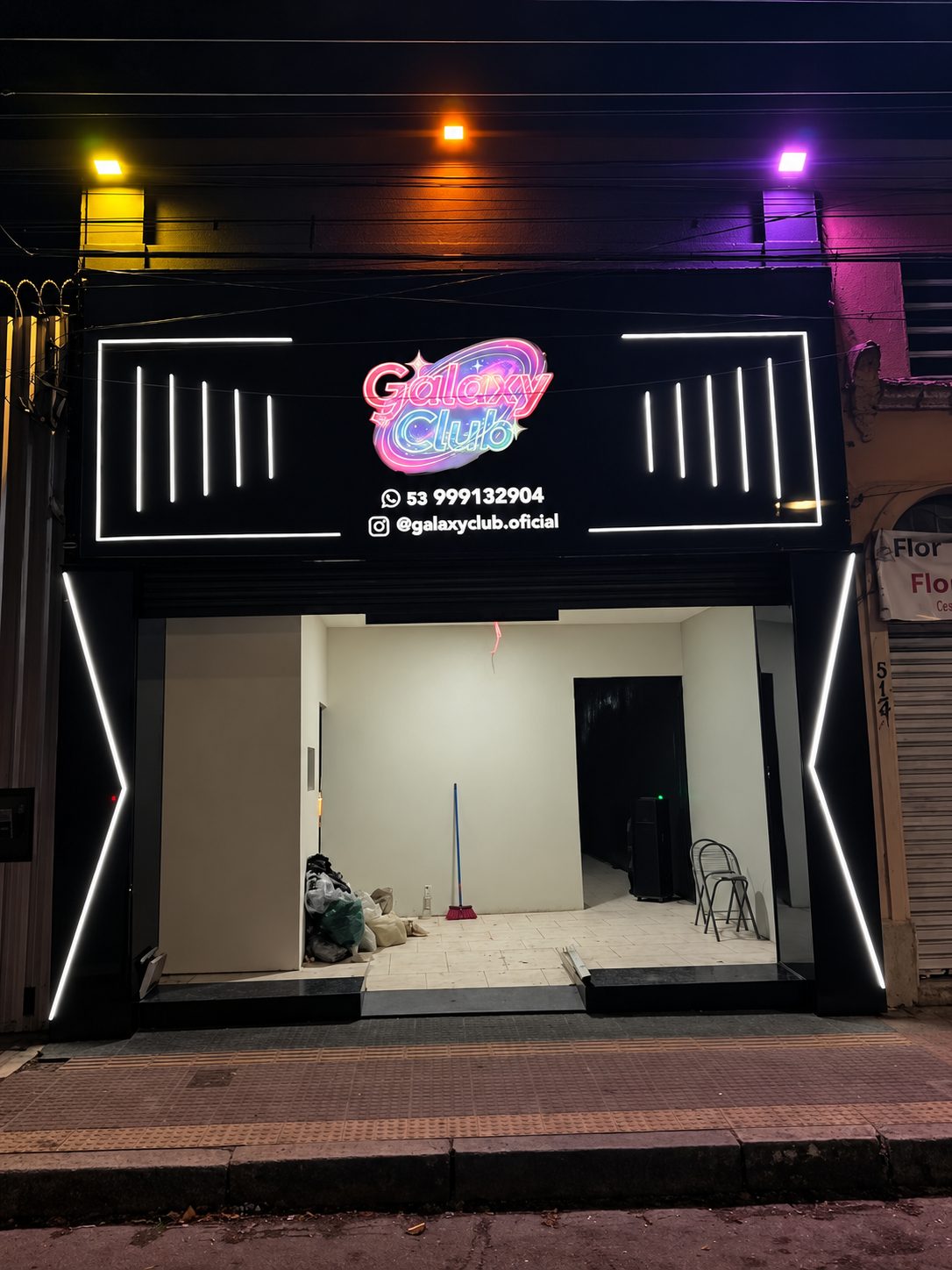 Fachada preta com perfis de LED branco e logotipo luminoso à noite