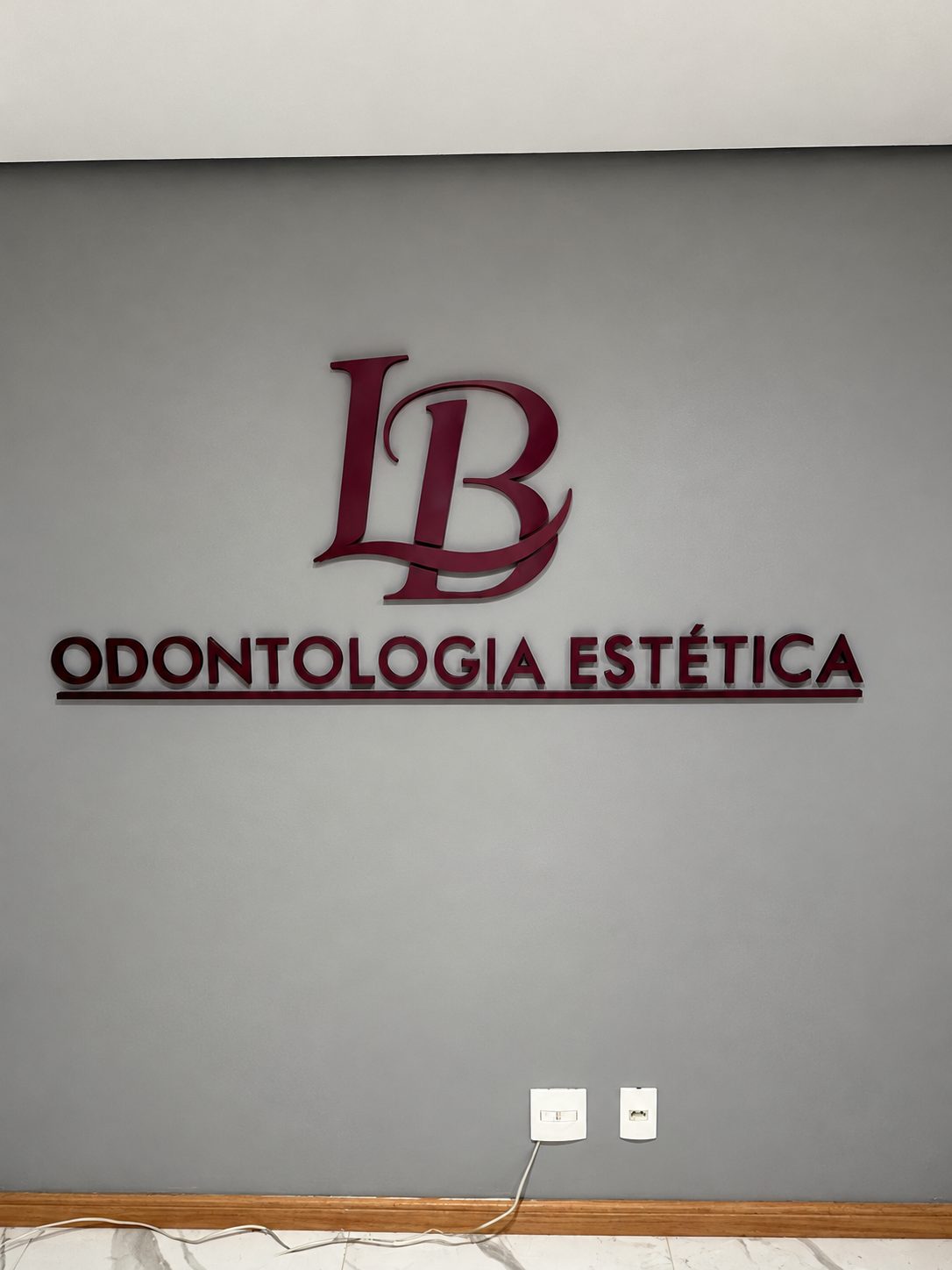 Letra caixa em relevo vinho aplicada em parede de clínica de odontologia
