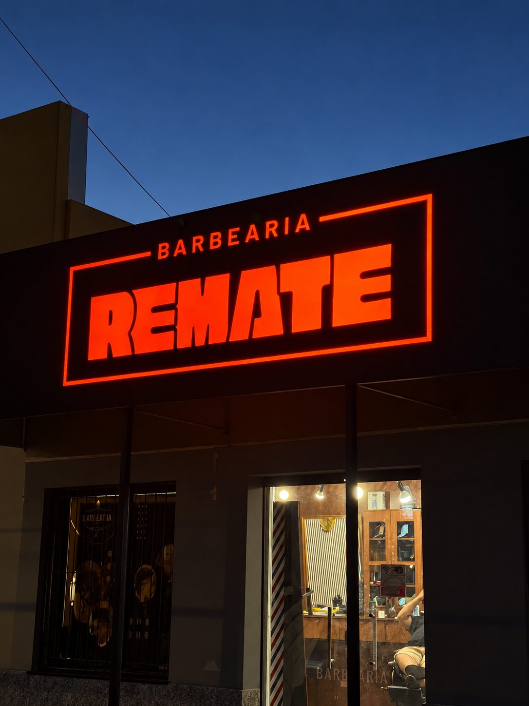 Letreiro luminoso em LED laranja de barbearia em Pelotas, iluminado à noite