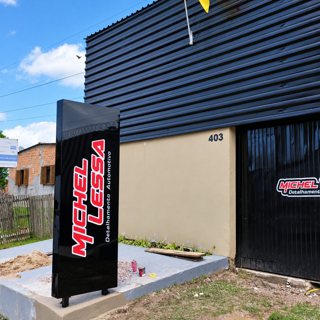 Totem vertical preto com logotipo vermelho em frente a oficina de detalhamento automotivo